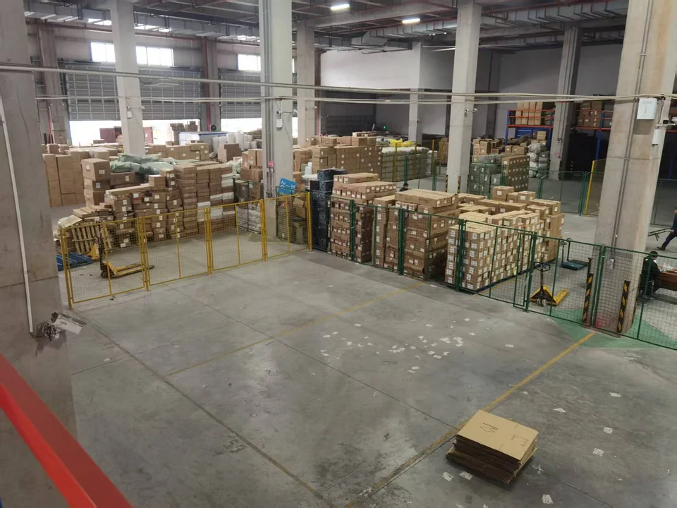 An organised China-side consolidation warehouse with labelled cargo zones, cartons and clear space for order coordination